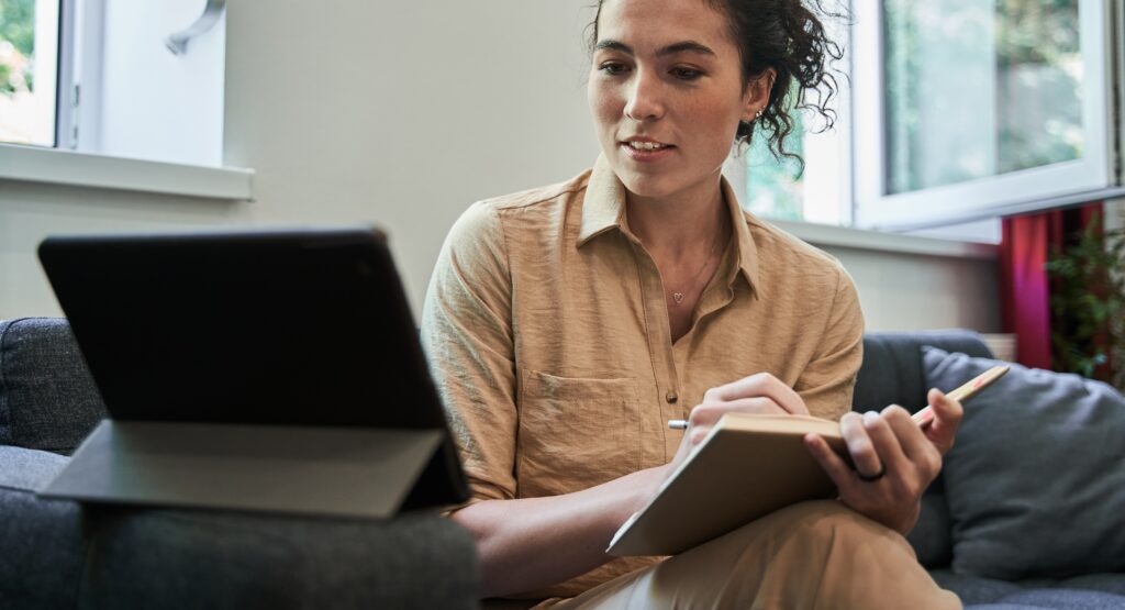 Female reading from an I-Pad and taking notes on managing cravings