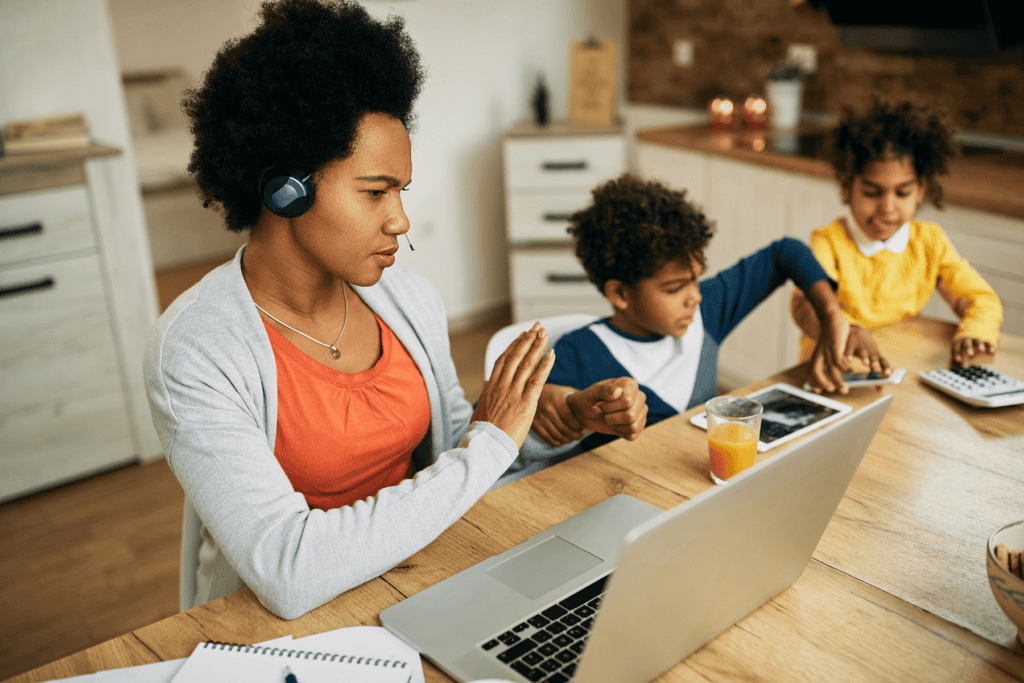 A photograph of a woman multitasking while working and care-taking